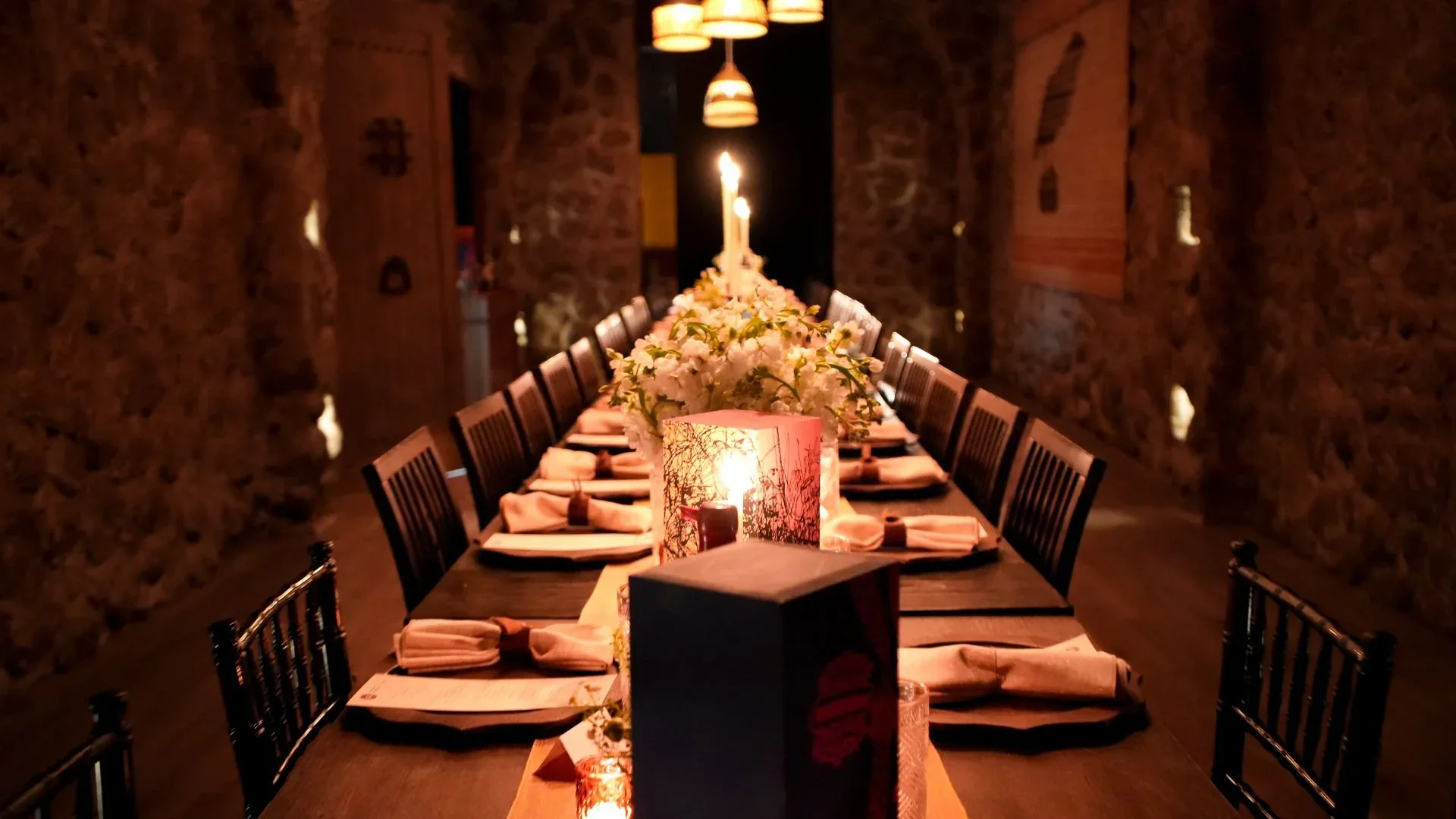 A candlelit long table between the stone walls of La Cava